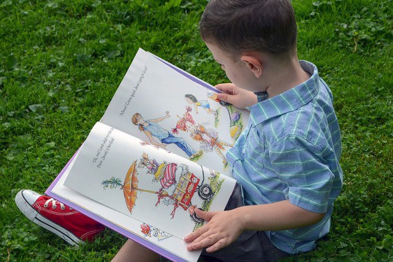 Foto niño leyendo en el pasto